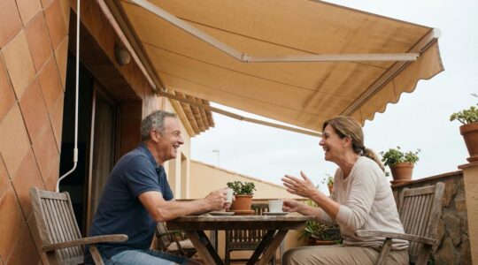 Toldo cofre extendido sobre terraza mediterránea con pareja disfrutando del exterior
